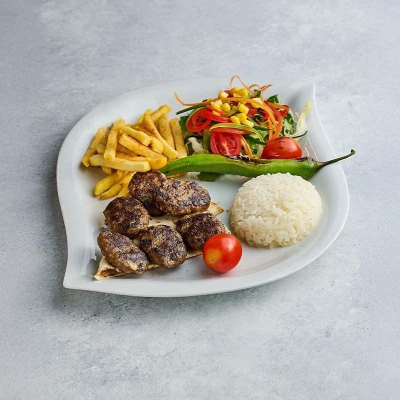 Bir tabakta köfte, patates kızartması, salata, közlenmiş biber ve pilav