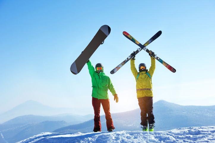 Kayak ve snowboard yapacak iki kişi ekipmanlarını gösteriyor