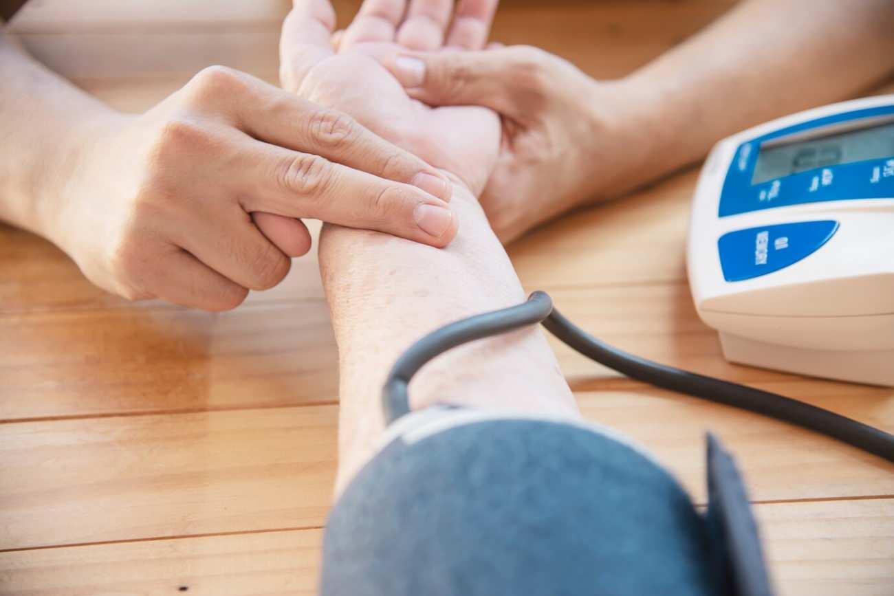 Bir sağlık uzmanı, hastanın nabzını ölçmek için bileğini kontrol ediyor