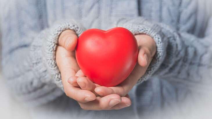 Ellerinde kırmızı kalp figürü tutan kişi