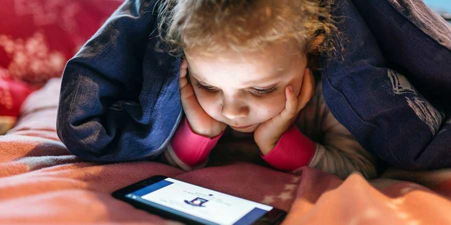 Telefon ile bir şeyler izleyen bir kız çocuğu