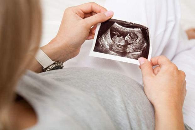 Elinde ultrason kağıdına bakan bir anne adayı