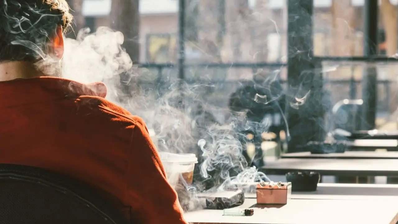 Sigara içerek etrafı duman altı yapan bir adam