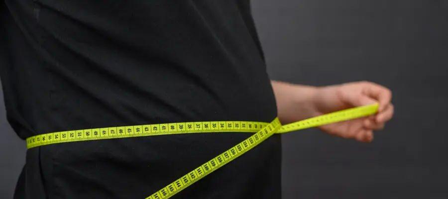 Bel çevresini mezura ile ölçen bir erkek